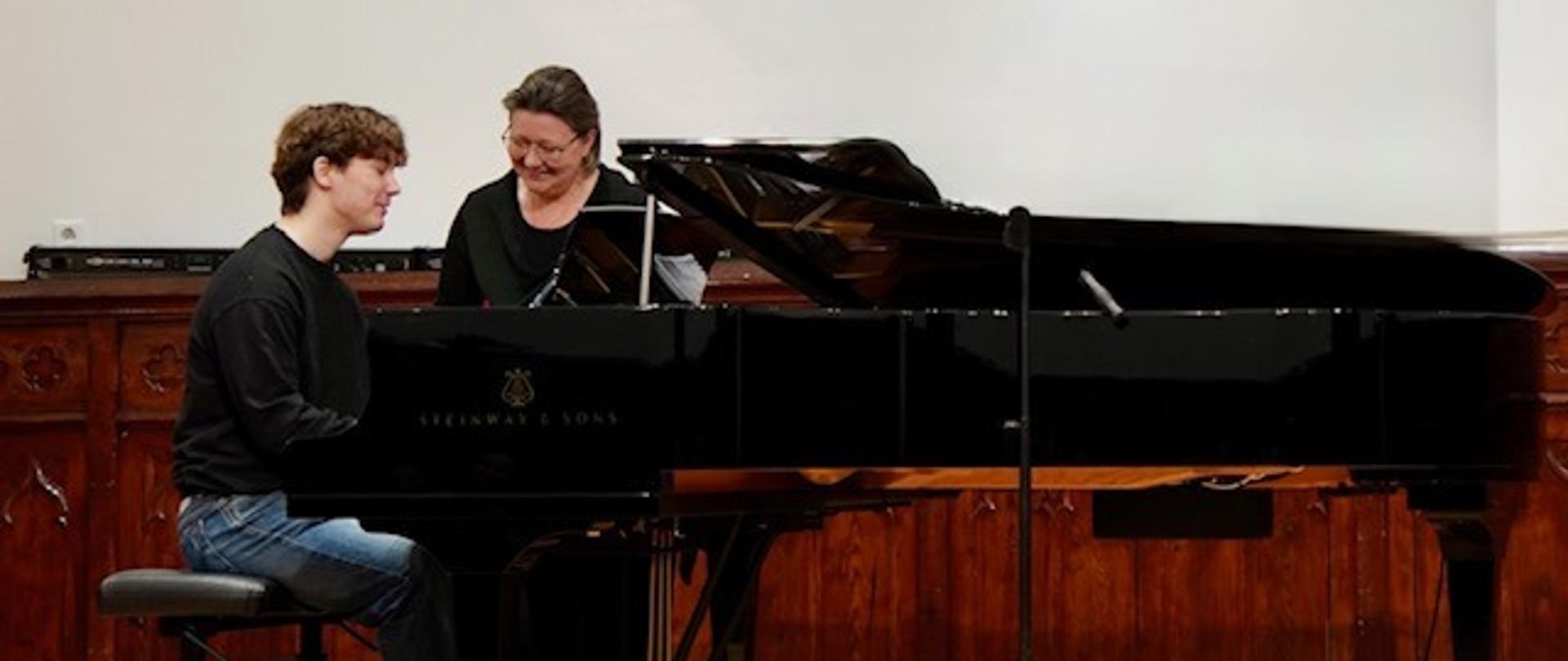 Uczestnik warsztatów gra na fortepianie, obok stoi prof. Aleksandra Nawe; wydarzenie odbyło się 11 lutego 2026 roku w szkole muzycznej.
