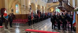 Strażacy uczestniczący w uroczystej mszy świętej. Z lewej strony widoczny poczet sztandarowy Komendy Powiatowej PSP w Zduńskiej Woli oraz wzdłuż kościoła ustawione poczty sztandarowe OSP. Z prawej strony w pierwszej ławce stoją komendanci PSP oraz prezesi OSP. 