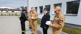 Zdjęcie przedstawia zakończenie szkolenia kierującego działaniem ratowniczym dla strażaka ratownika Ochotniczych Straży Pożarnych (Dowódcy OSP), świadectwa sa wręczane na placu komendy.