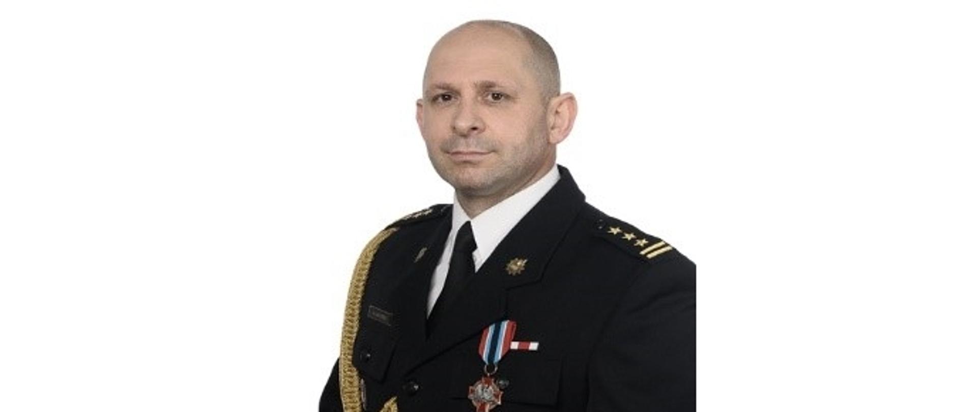 Na zdjęciu w mundurze wyjściowym na jasnym tle Zastępca Komendanta Miejskiego Państwowej Straży Pożarnej w Przemyślu st. bryg. Grzegorz Latusek