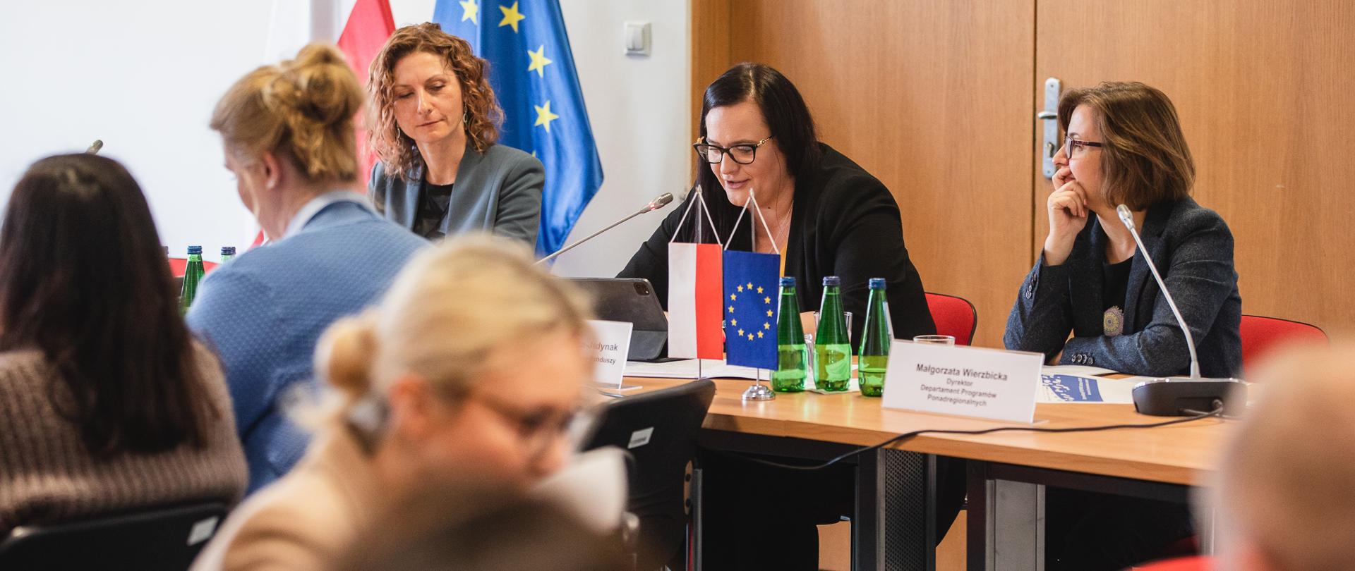 Grup osób na spotkaniu siedzi przy stołach. Wśród nich wiceminister Małgorzata Jarosińska-Jedynak.