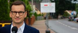 Premier Mateusz Morawiecki w trakcie konferencji prasowej w Dłutówce. W tle droga;