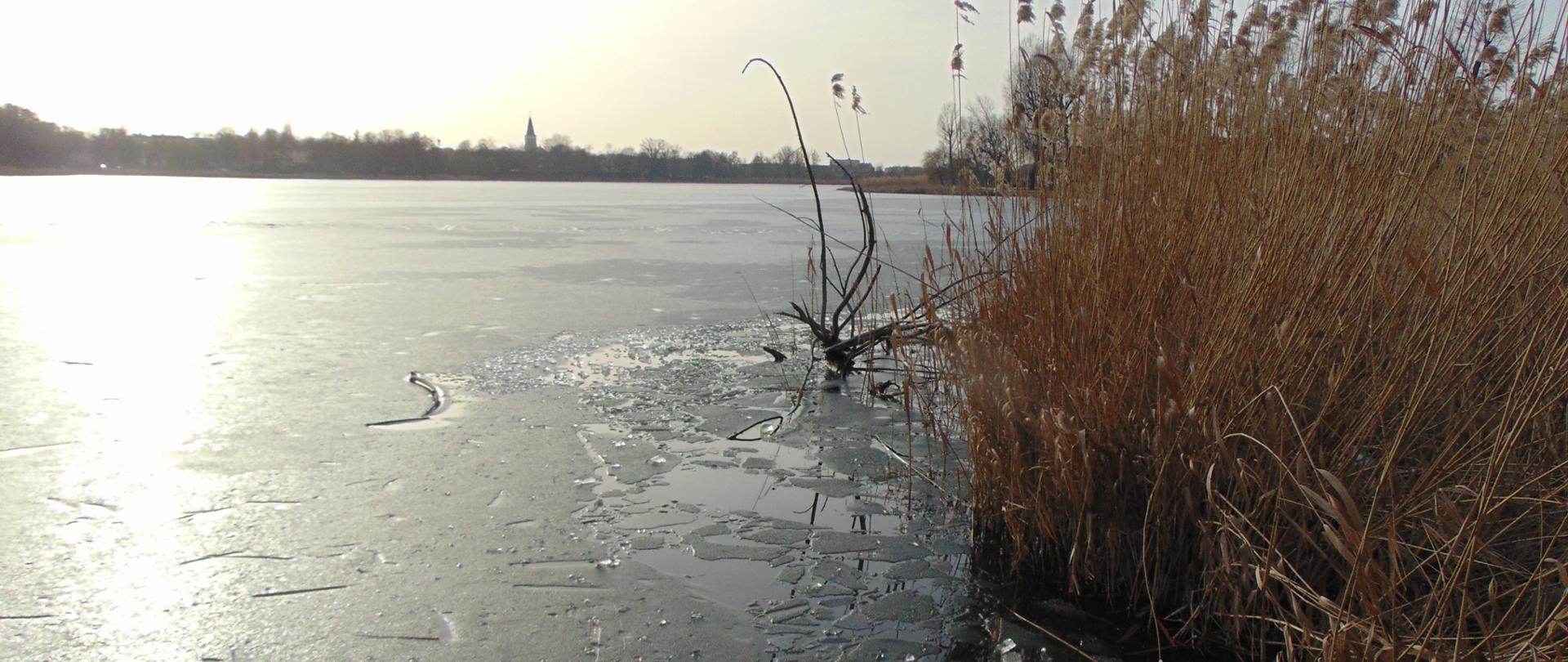 widok jeziora z cienką taflą lodu