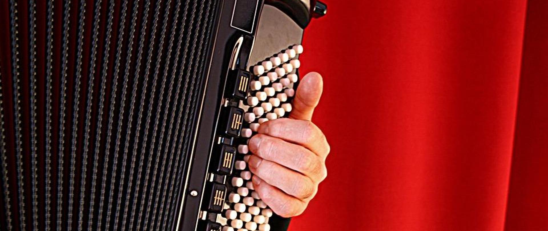 Po lewej miech oraz lewy manuał akordeonu, po prawej czerwony materiał służący jako tło