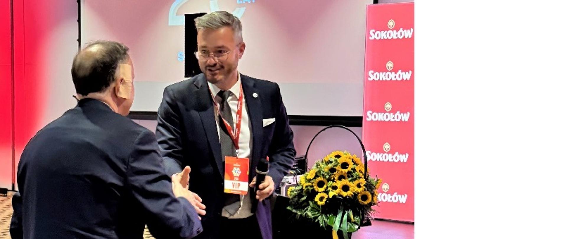 Prezes Leszek Szymański składa gratulacje i wręcza pamiątkowy grawerton Przemysławowi Gostkiewiczowi, prezesowi spółki Sokołów S.A.