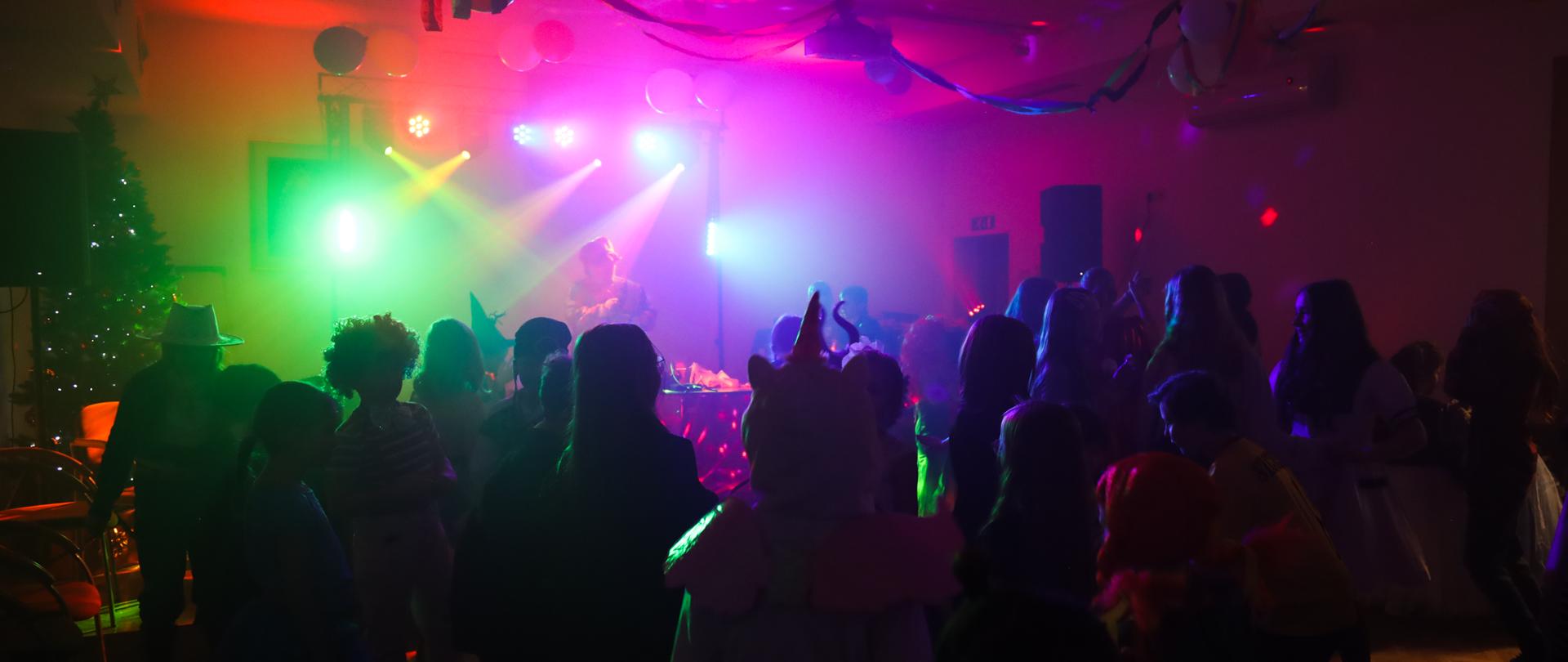 uczniowie bawiący się na balu, dużo kolorowych migających świateł