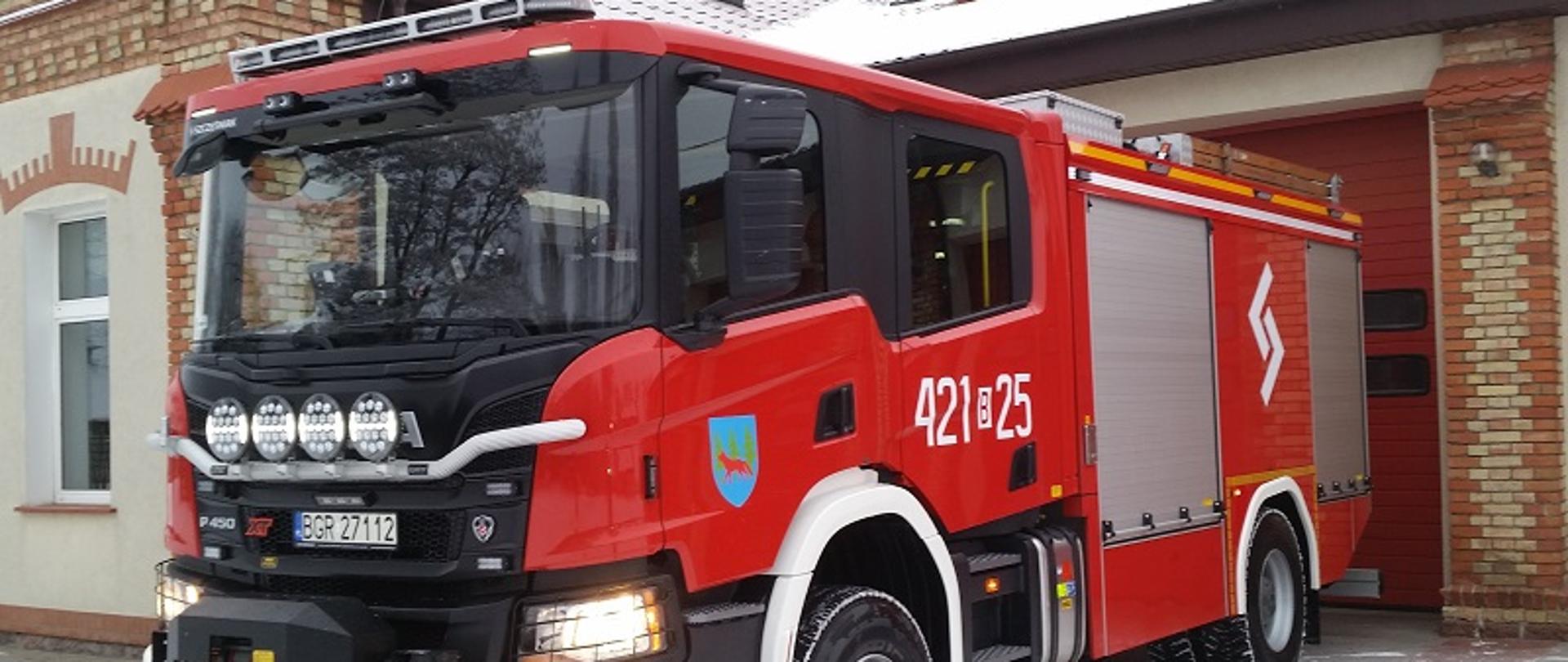 Ciężki samochód gaśniczy stoi przed budynkiem KPPSP Grajewo