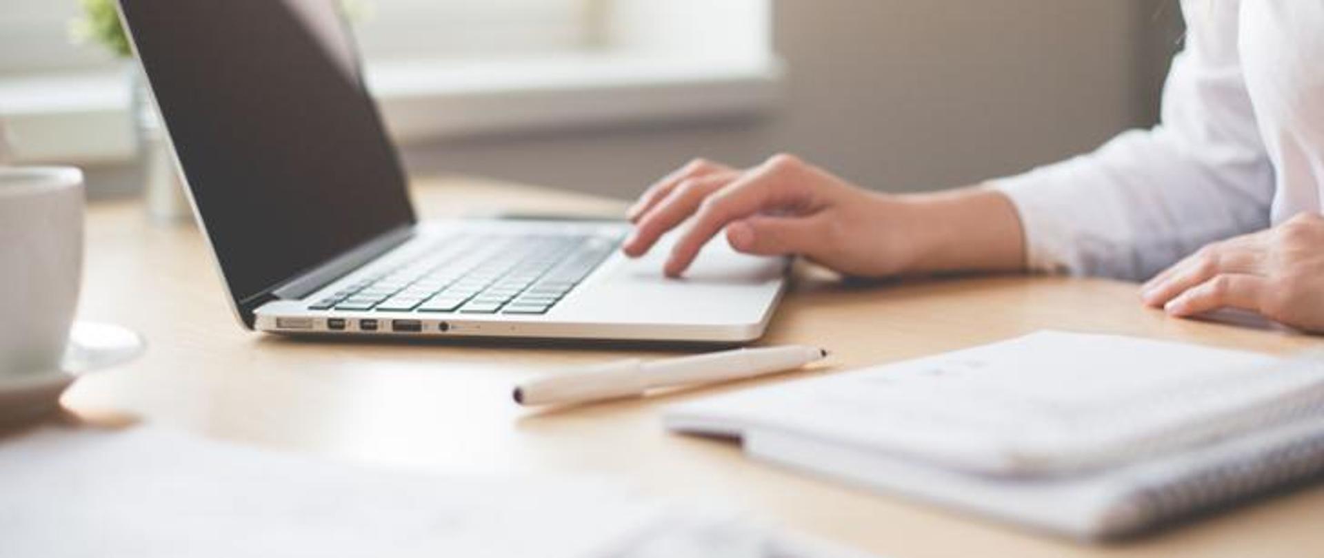 Jedna osoba siedząca przy biurku i używająca laptopa