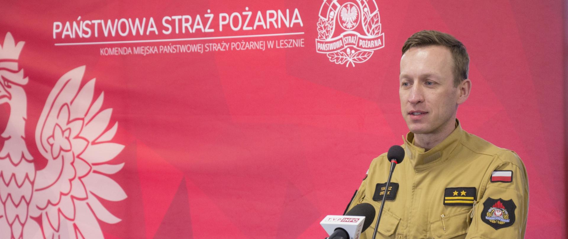 Strażak PSP stoi przy mównicy i przemawia.