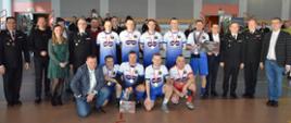 zwycięska drużyna oraz organizatorzy i goście turnieju pozują do zdjęcia w hali sportowej