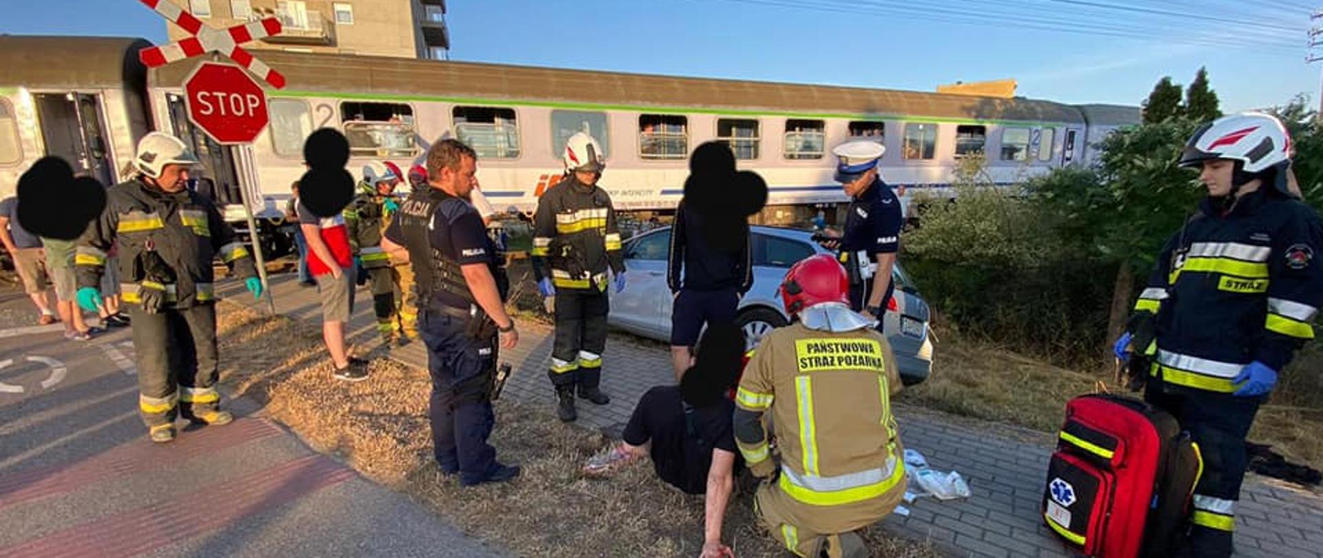 Na zdjęciu widoczni ratownicy Państwowej i Ochotniczej Straży Pożarnej udzielający pomocy medycznej poszkodowanej osobie