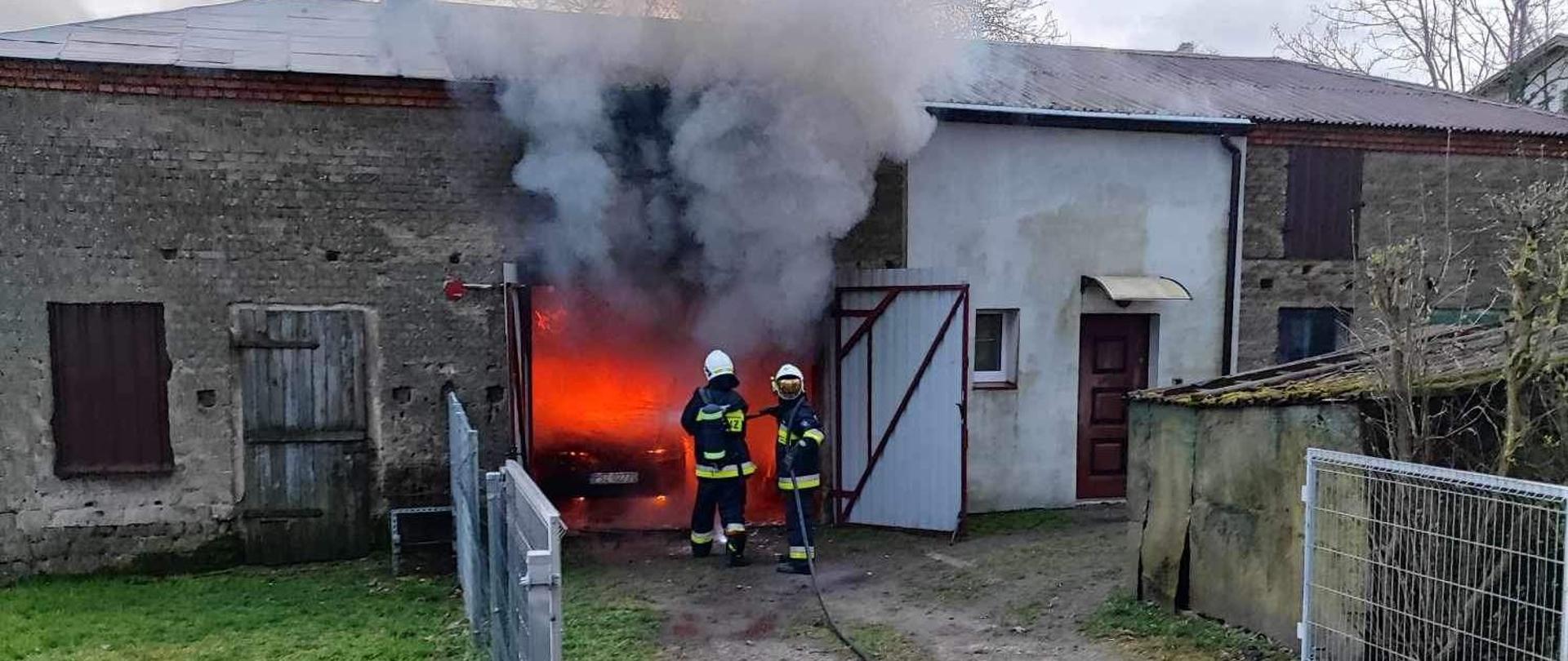 Strażacy gaszą samochód w garażu
