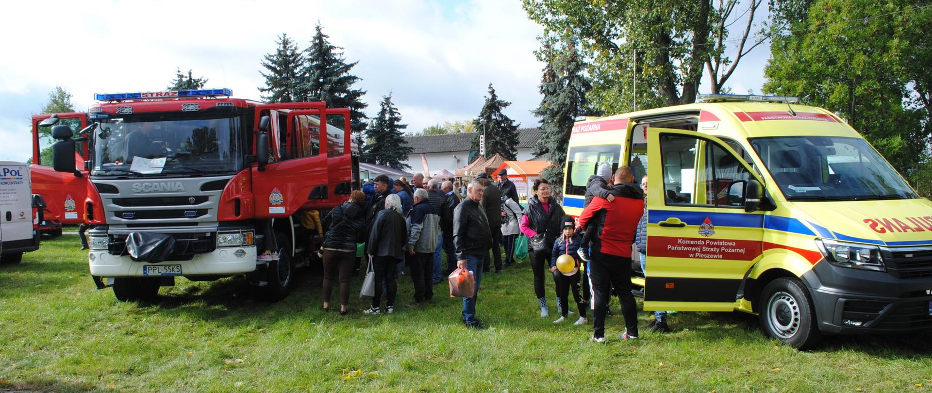 Ciężki wóz gaśniczy oraz karteka ratunkowa pleszewskiech strażaków stoją przodem, pomiędzy nimi widać tłum ludzi przyglądających się wystawionemu sprzętowi