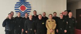 Zdjęcie grupowe uczestników spotkania. Na zdjęciu 13 oficerów w tle logo CNBOP. 