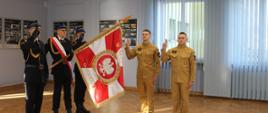 Na zdjęciu poczet sztandarowy Komendy Miejskiej PSP w Piotrkowie Trybunalskim, z prawej strony dwóch strażaków z uniesionym prawym ramieniem składają ślubowanie. 