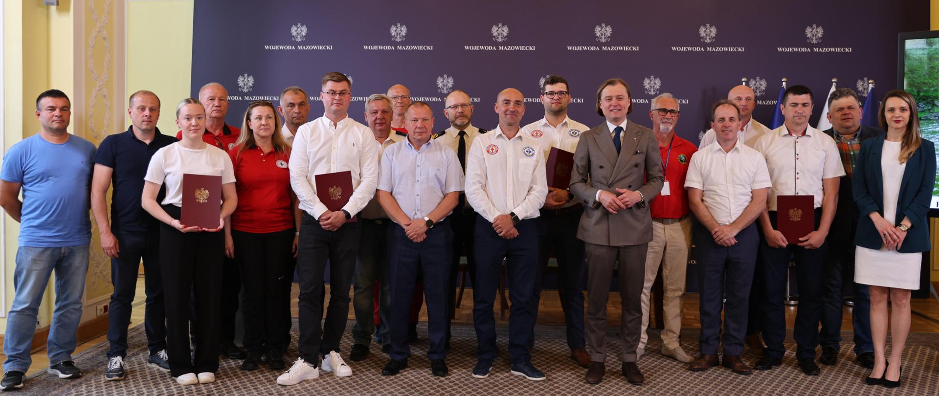 Na zdjęciu grupa ludzi z teczkami ze złotym orłem