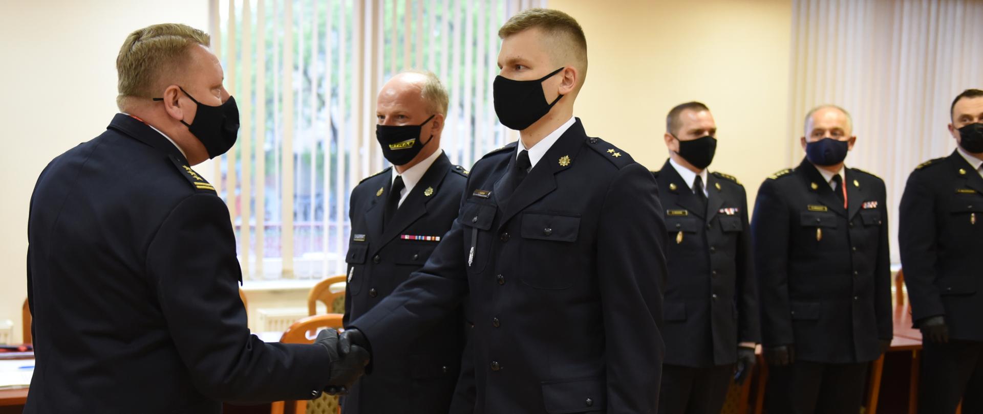 Na zdjęciu widać st. bryg. Grzegorza Janowskiego gratulującego skierowania absolwentowi SGSP, na drugim planie 4 komendantów powiatowych 