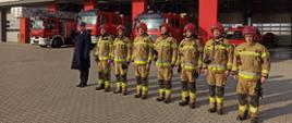 Zdjęcie przedstawia ośmiu strażaków przed Komendą