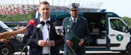 Briefing inaugurujący rozpoczęcie akcji „Bezpieczny Autokar – wakacje 2023” na parkingu koło Stadionu Narodowego w Warszawie. Na pierwszym planie (od lewej): z zapewnieniu bezpieczeństwa dzieciom i młodzieży podczas letniego wypoczynku mówi Minister Edukacji i Nauki Przemysław Czarnek. W tle: za Ministrem Edukacji i Nauki stoi Główny Inspektor Transportu Drogowego Alvin Gajadhur i oznakowany furgon Inspekcji Transportu Drogowego.