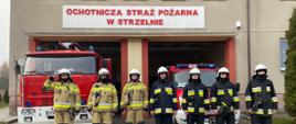 Strażacy stojąc na baczność na tle samochodów gaśniczych oddają cześć poległym strażakom z Ukrainy.