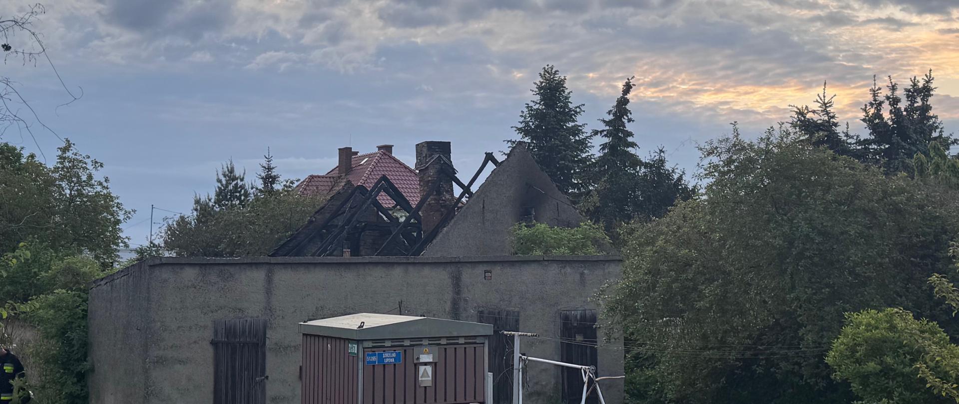 Widok na budynek po ugaszeniu pożaru. Widoczna nadpalona konstrukcja dachu