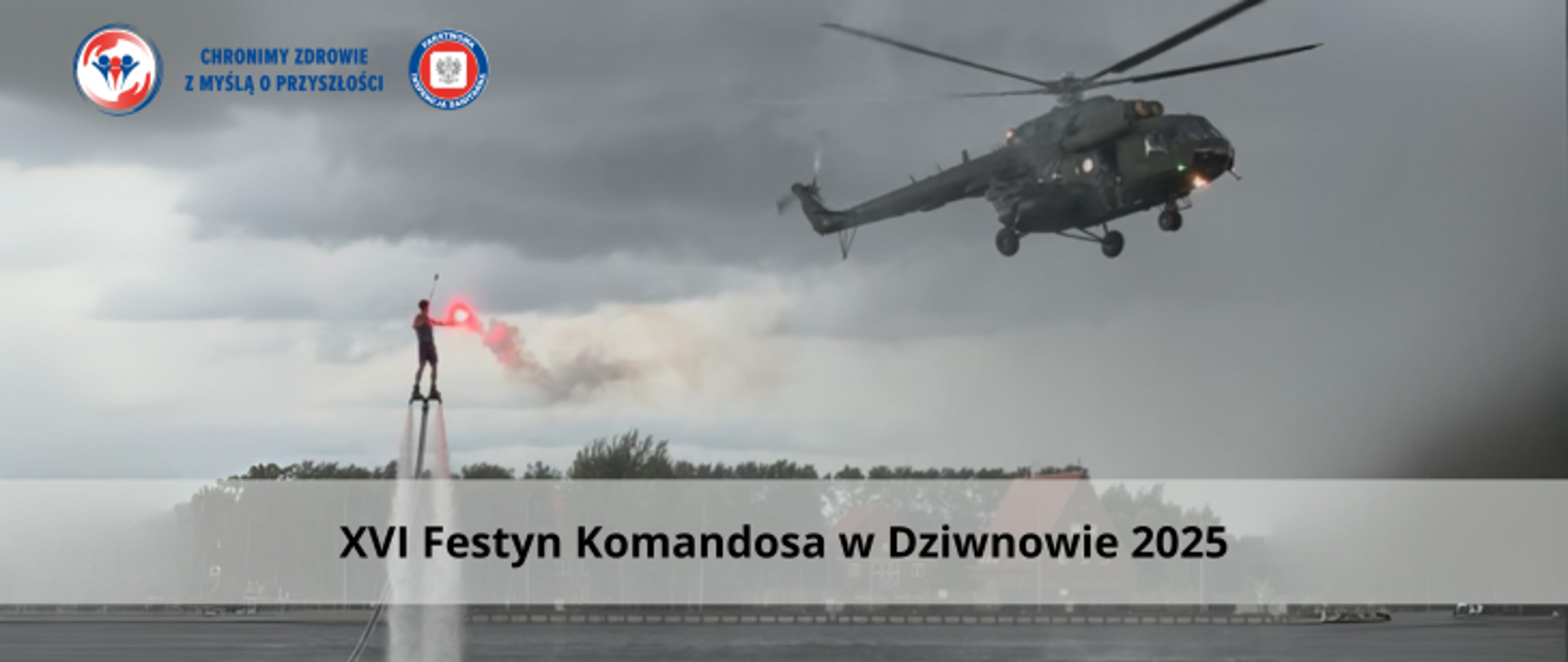 Grafika przedstawia wojskowy helikopter na tle szarego pochmurnego nieba. Po lewej stronie znajduje się mężczyzna który utrzymuje się nad wodą dzięki flayboard. w ręku trzyma czerwoną racę, z której wydostaje sie dym. W tle widać zarośla oraz budynki. Na dole zdjęcia umieszczono napis XVI Festyn Komandosa w Dziwnowie. W lewym górnym rogu umieszczono dwa logo Inspekcji Sanitarnej oraz napis Chronimy Zdrowie z Myślą o przyszłości. 