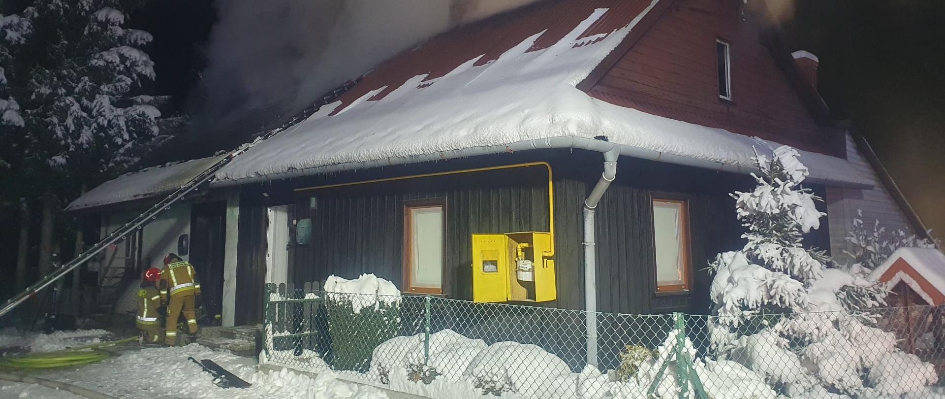 Dwóch strażaków gaszących pożar budynku 