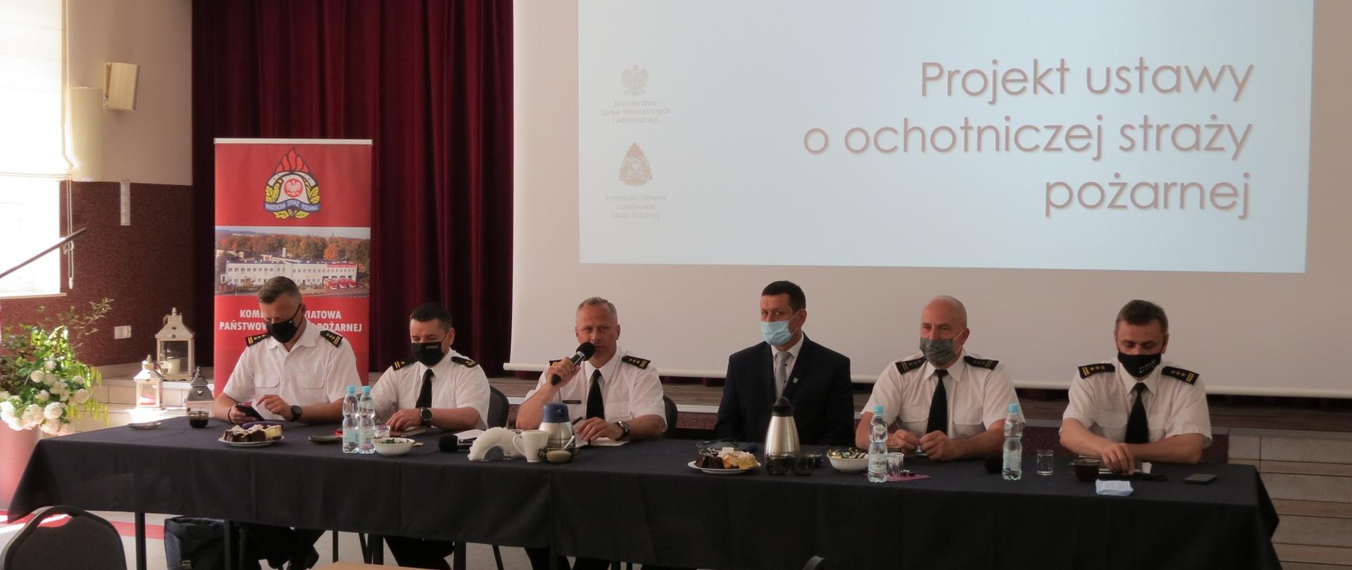 Zdjęcie przedstawia przemawiającego Zastępcę Kujawsko-Pomorskiego Komendanta Wojewódzkiego Państwowej Straży Pożarnej st. bryg. Robert Wiśniewskiego. Wraz z nim przy stole Komendant Miejski PSP w Grudziądzu st. bryg. Robert Gutowski, Komendant Powiatowy PSP w Rypinie st. bryg. Grzegorz Łydkowski, Komendant Powiatowy PSP w Golubiu-Dobrzyniu mł. bryg. Witold Juszczak, Komendant Powiatowy PSP w Brodnicy st. bryg. Waldemar Szrull, oraz Przewodniczący Rady Gminy Bobrowo Ryszard Włodarczyk.