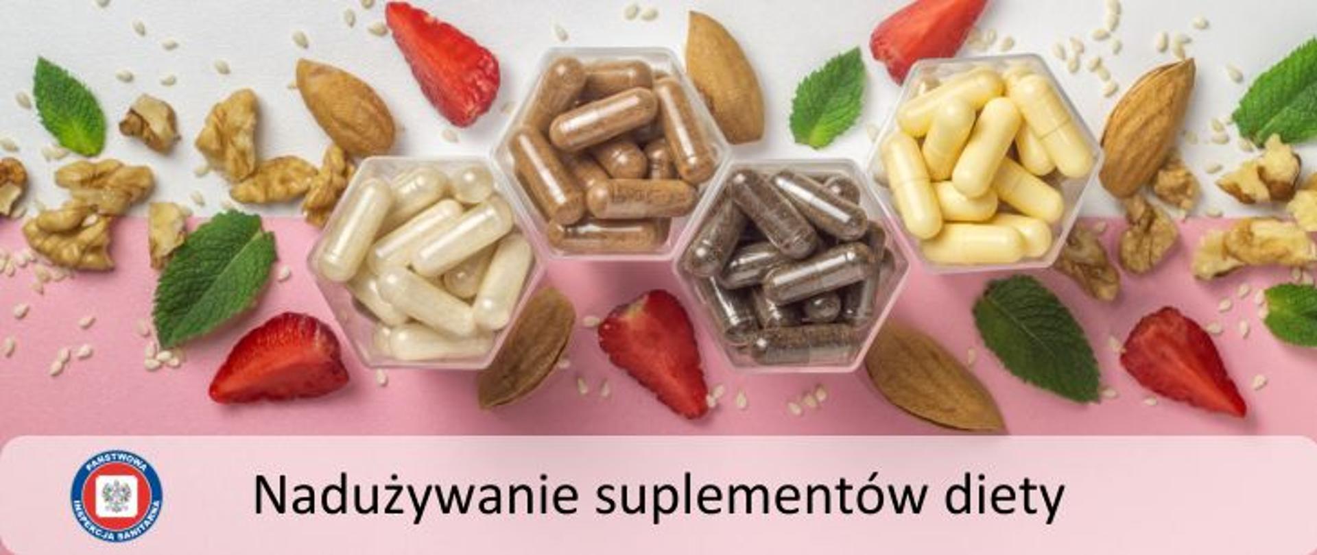 Na biało-różowym tle widoczne cztery pojemniczki z różnymi suplementami diety w formie kapsułek. Wokół poukładane cząstki czerwonych truskawek, orzechów włoskich, migdałów oraz zielone liście mięty. Na dole napis Nadużywanie suplementów diety. W lewym dolnym rogu logo Państwowej Inspekcji Sanitarnej.