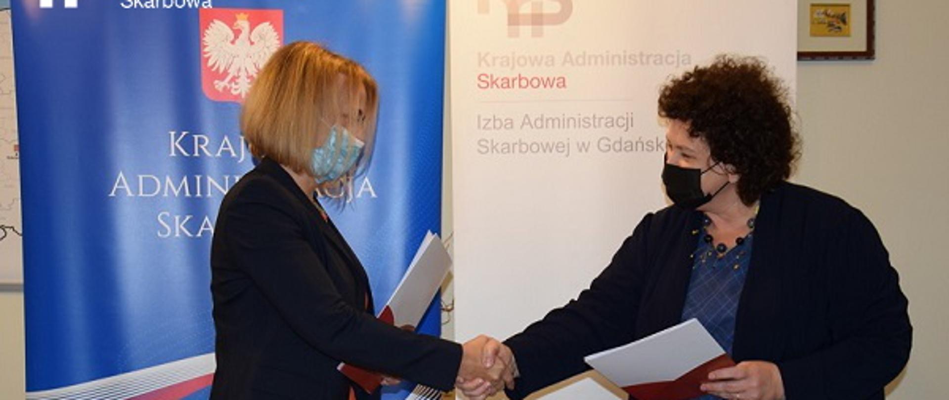 Uścisk dłoni Pomorskiej Wojewódzkiej Inspektor Ochrony Środowiska dr inż. Edyty Witka-Jeżewskiej oraz Dyrektor Izby Administracji Skarbowej w Gdańsku Barbary Bętkowskiej-Cela po podpisaniu porozumienia.