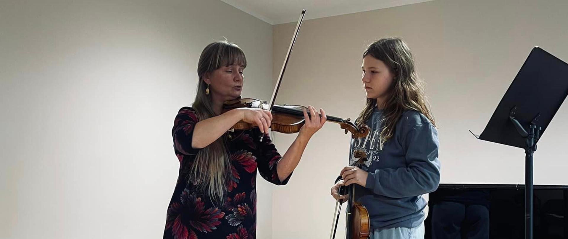 Wykładowczyni stoi na scenie razem z uczennicą, prezentuje sposób gry