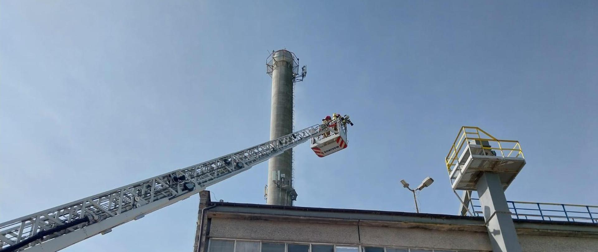 Drabina mechaniczna rozstawiona nad dachem budynku produkcyjnego