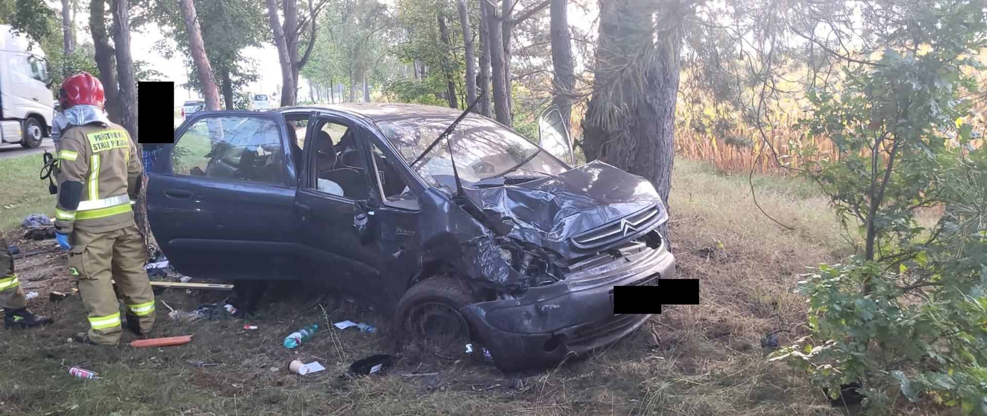 Ciemny, uszkodzony samochód znajduje się w lesie, widok od przodu