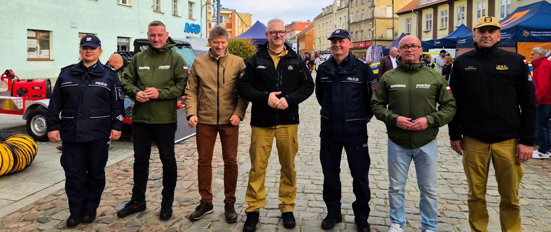 grupa oficjeli, w tym wojewoda, stoją wzdłuż drogi podczas wydarzenia, pozują do zdjęcia 