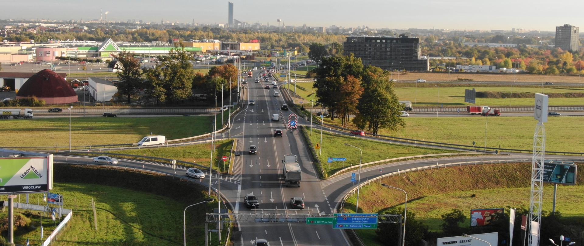 na zdjęciu widoczny węzeł autostradowy. Na jezdni pojazdy, w tle budynki