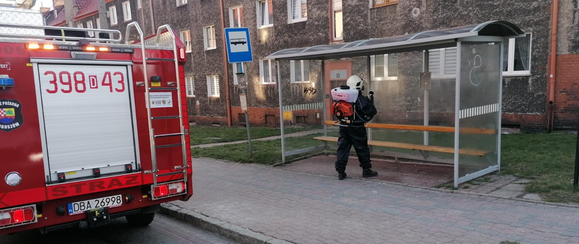 Strażak dokonuje oprysku przystanku