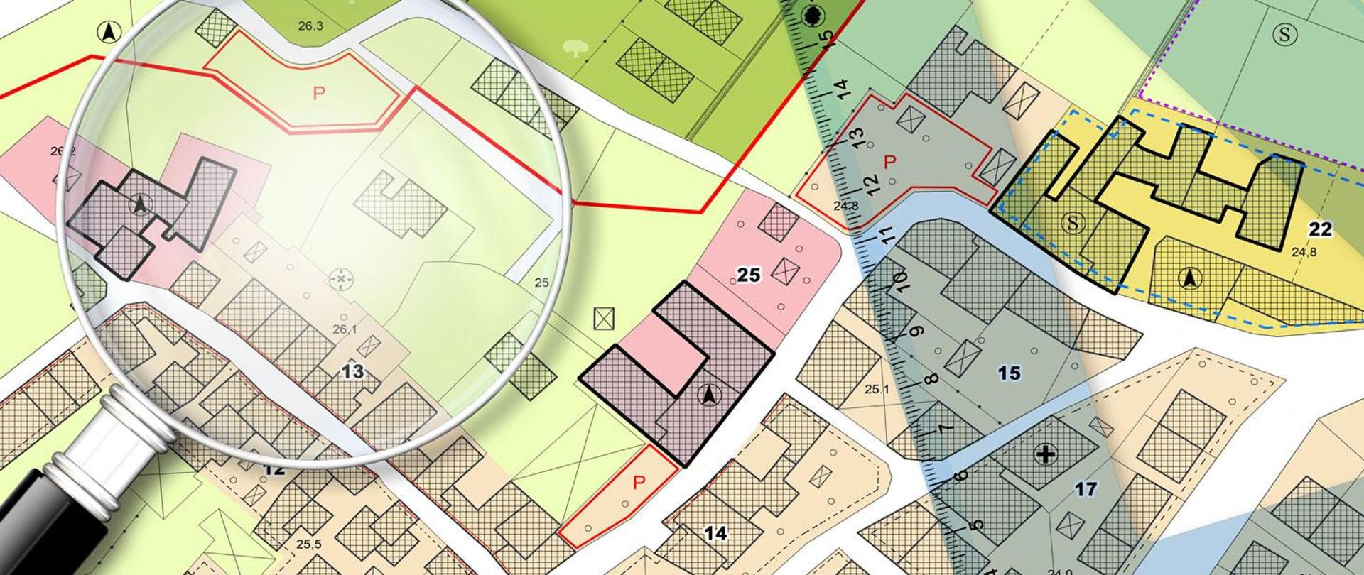 widok z góry na mapę z rozrysowanymi zabudowaniami. Na makie po prawej stronie leży przeźroczysta linijka a po lewej stronie duża lupa z czarnym uchwytem