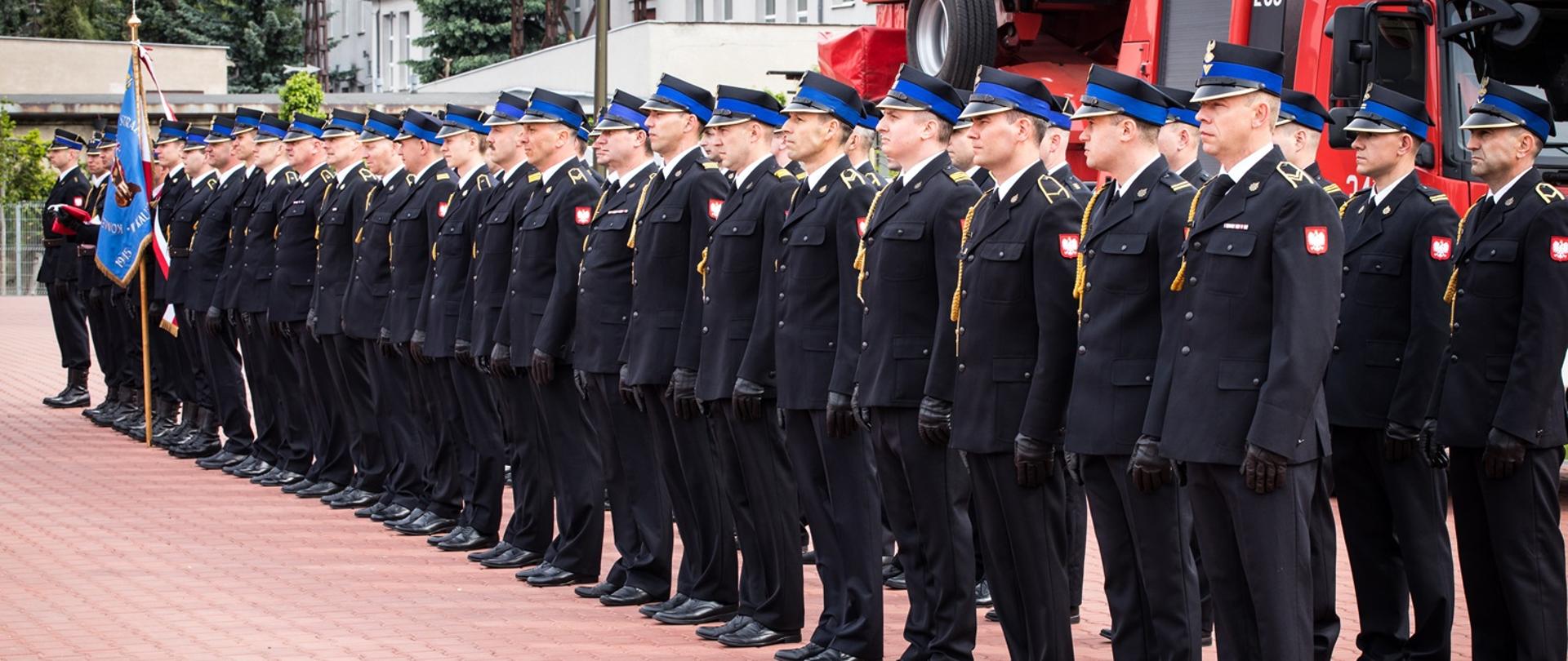 Strażacy stoją w dwuszeregu.