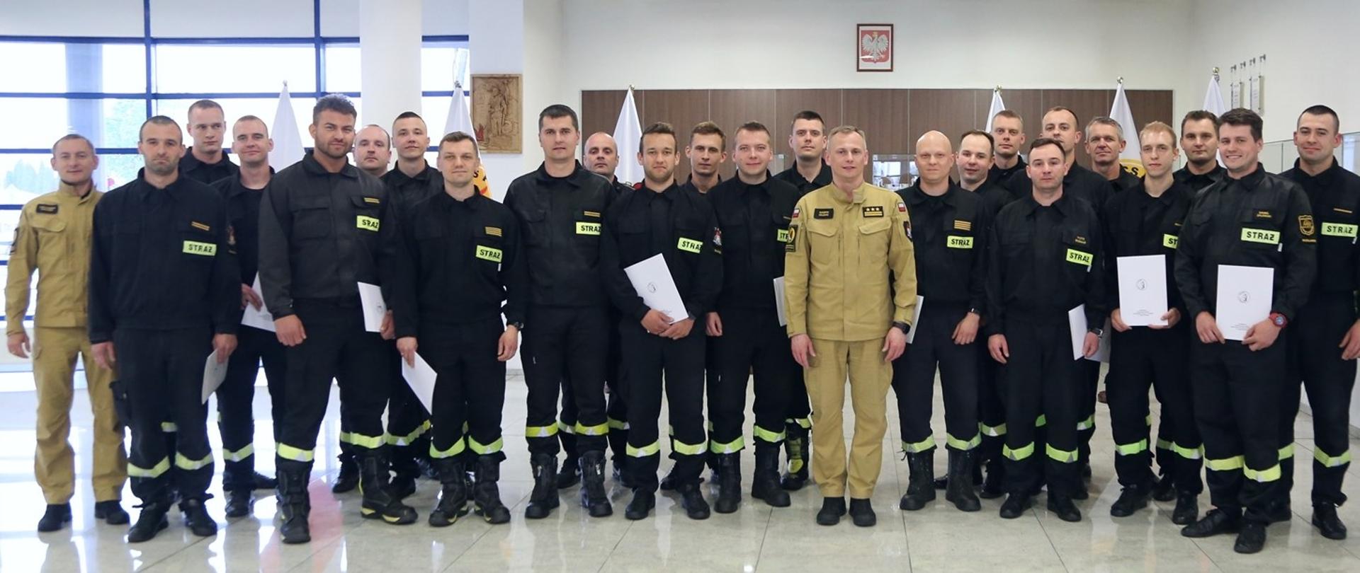 Grupowe zdjęcie uczestników szkolenia (23 funkcjonariuszy PSP) w towarzystwie Zastępcy Komendanta Centralnej Szkoły PSP oraz funkcjonariusza CS PSP