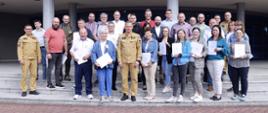 Grupowe zdjęcie uczestników szkolenia (28 osób) w towarzystwie Zastępcy Komendanta Centralnej Szkoły PSP, dwóch funkcjonariuszy CS PSP oraz kobiety