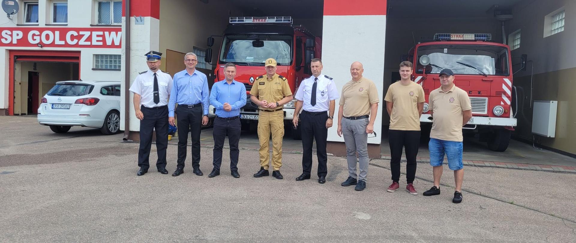 Nadbryg. Jarosław Tomczyk wraz z druhami OSP Golczewo na tle ich remizy. W bramach widoczne samochody ratowniczo gaśnicze.
