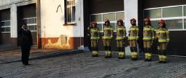 Zdjęcie przedstawia strażaków z Jednostki Ratowniczo-Gaśniczej Państwowej Straży Pożarnej w Lwówku Ślaskim podczas uroczystej zmiany służby. Strażacy stojący w szeregu.