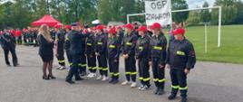 Zawodnicy młodzieżowej drużyny pożarniczej w ubraniach strażackich podczas wręczania medali po zakończonej rywalizacji. Medale wręcza komendant powiatowy Państwowej Straży Pożarnej w Dębicy.