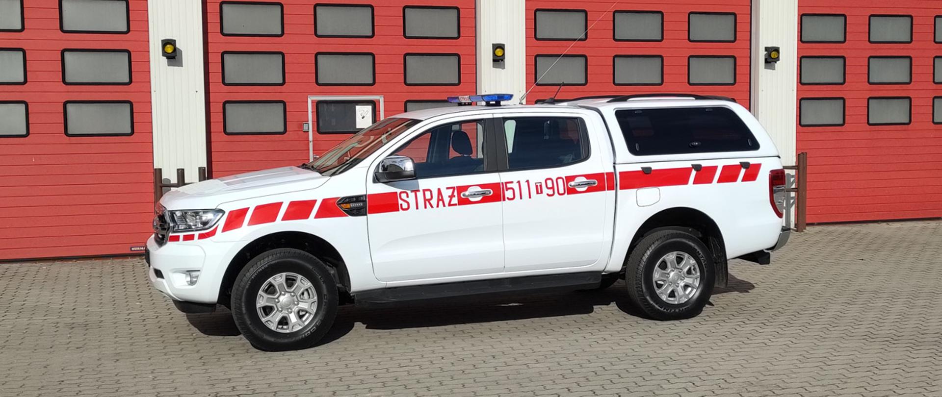 Samochód specjalny rozpoznawczo ratowniczy koloru białego, kryptonim operacyjny 511-90 na drugim planie bramy garażowe