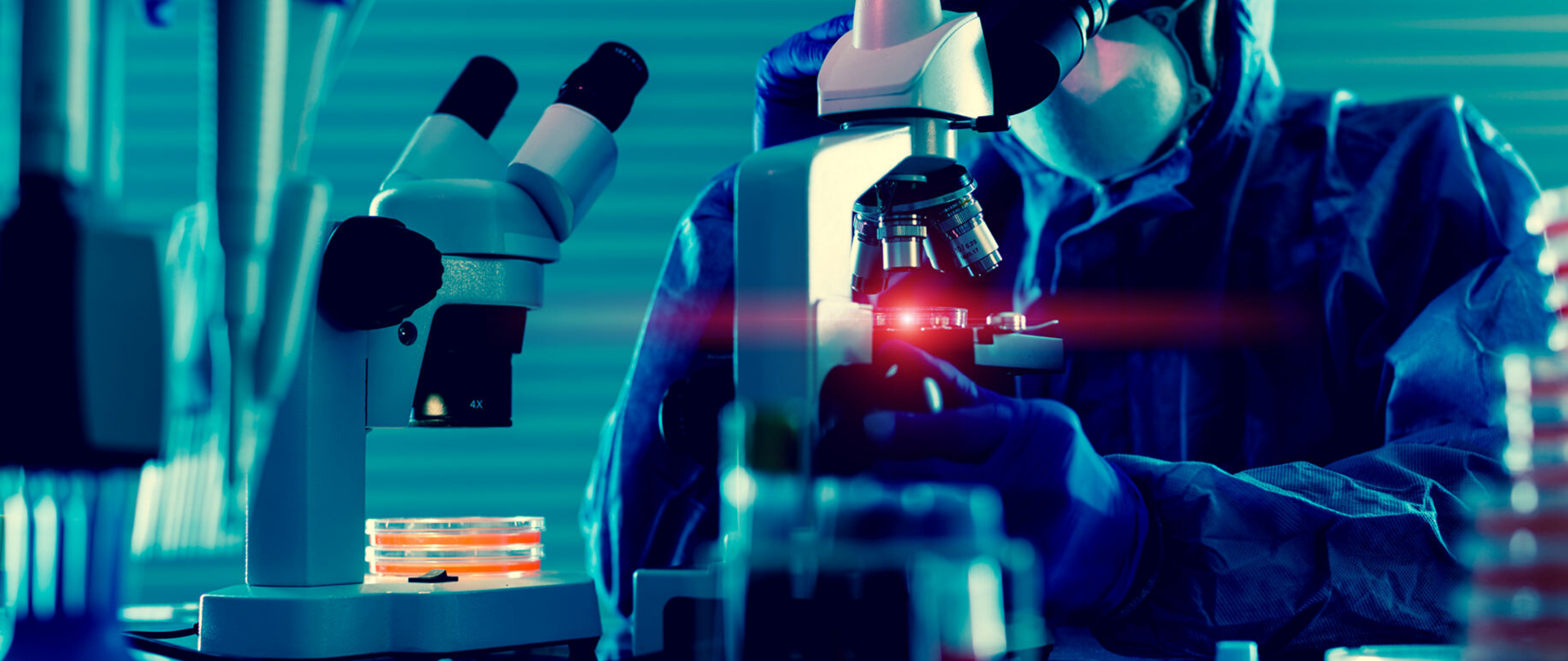 Człowiek z masce ochronnej przy mikroskopie.