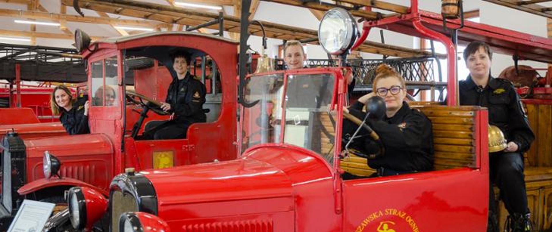 Funkcjonariuszki PSP przy zabytkowych samochodach strażackich.