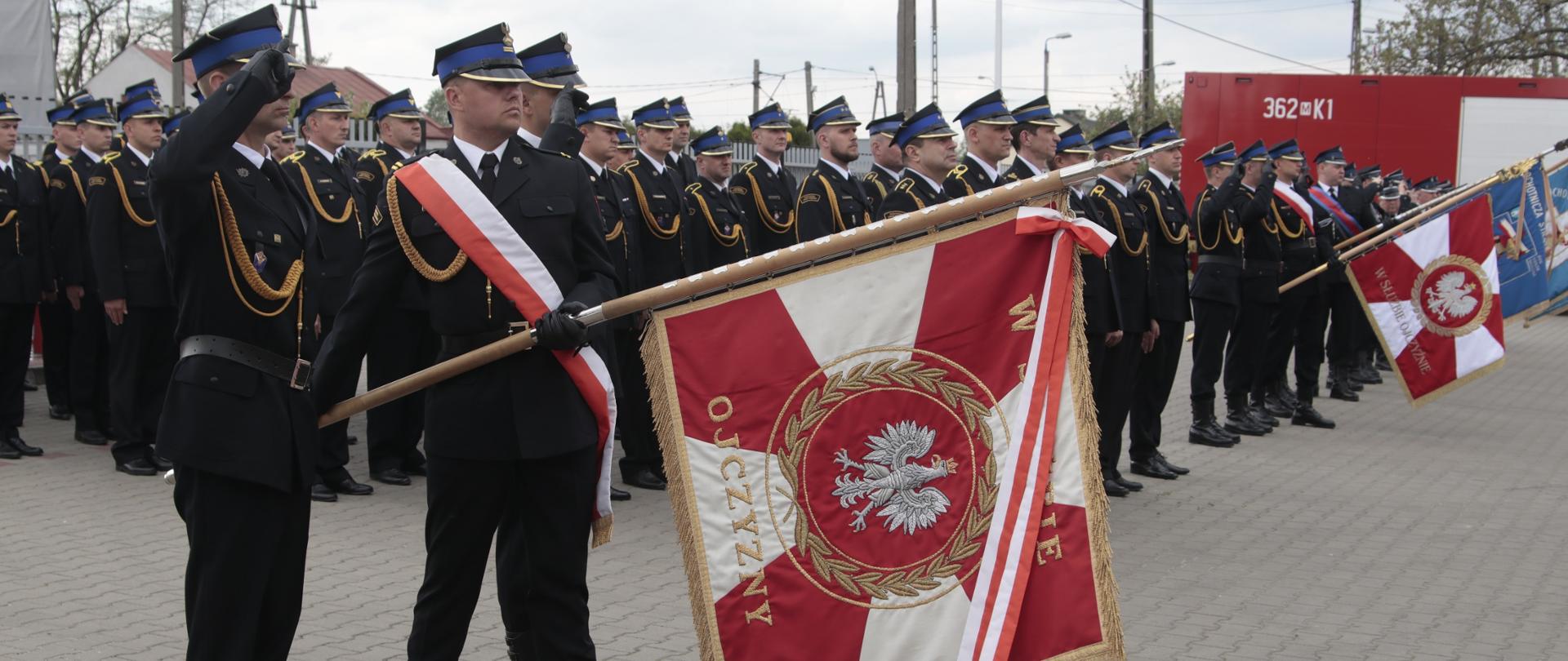 Na zdjęciu salutujący sztandar KM PSP w Płocku i pododdział strażaków