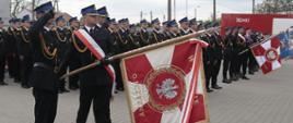 Na zdjęciu strażacy w mundurach galowych, salutujące sztandary i pododdział strażaków.