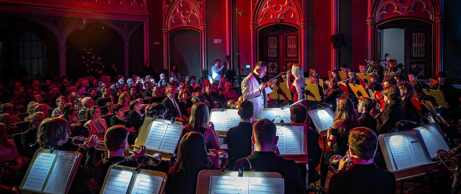 Orkiestra dęta podczas koncertu w tle publiczność