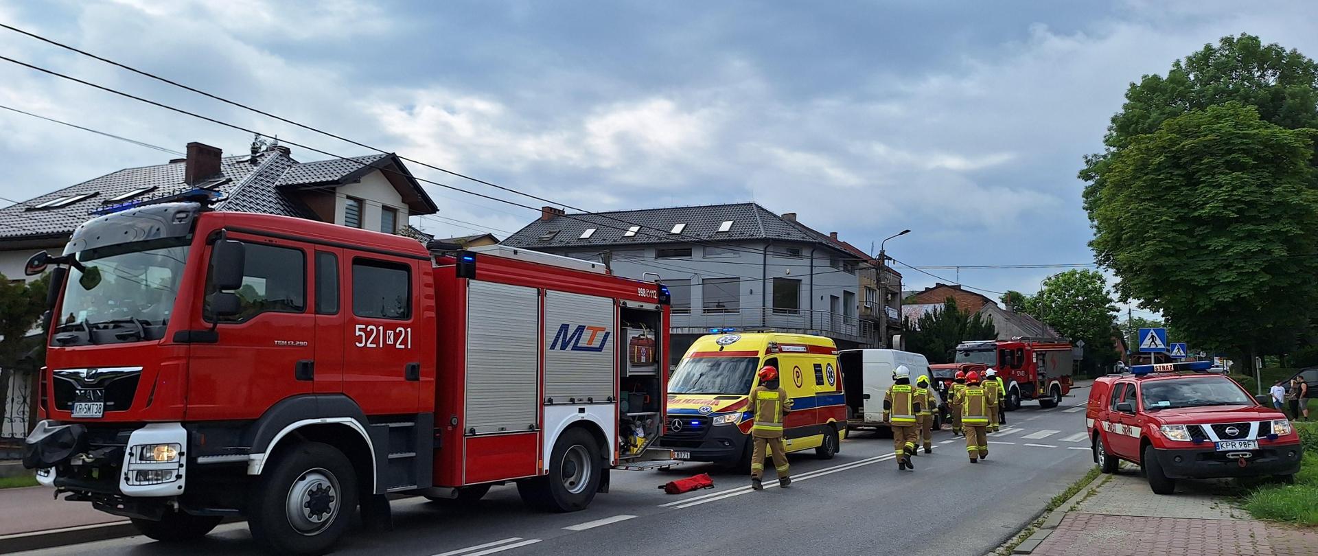 samochody strażackie stoją na jednym pasie drogi podczas wypadku. Strażacy udają się na miejsce wypadku,